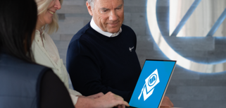 A man and a woman looking at a laptop showing Monitor Academy logo