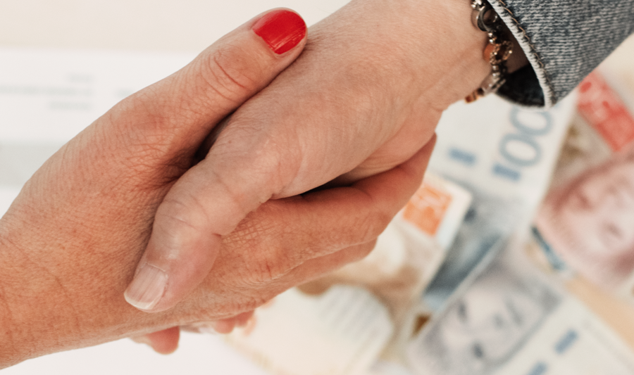 A handshake between two people. A contract and some money is laying on the table.