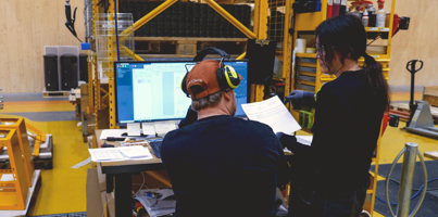 Två personer står i en fabrik och kollar på en dator med Monitor ERP dashboard