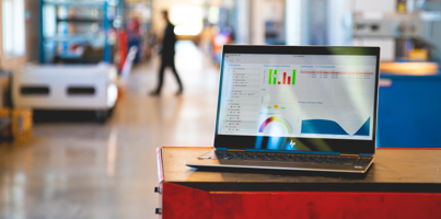 Monitor ERP dashboard displayed on a laptop in a factory environment.