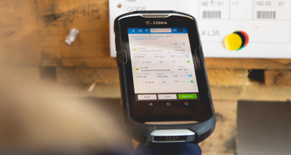 Person in a warehouse scanning pallet labels using a handheld scanner. 