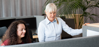 Medarbetare på supporten står och hanterar ett ärende vid en dator.