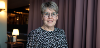 Linda Näslund, redovisningsansvarig på Olofsfors står framför en gardin.