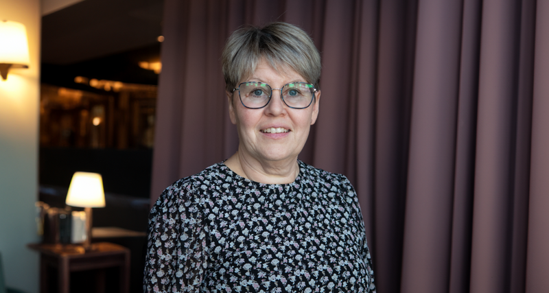 Linda Näslund, redovisningsansvarig på Olofsfors står framför en gardin.