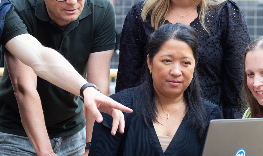 Medarbetare sitter runt ett bord och kollar på en dator.