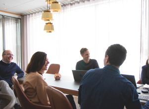 A group of people sitting around a table with laptops.