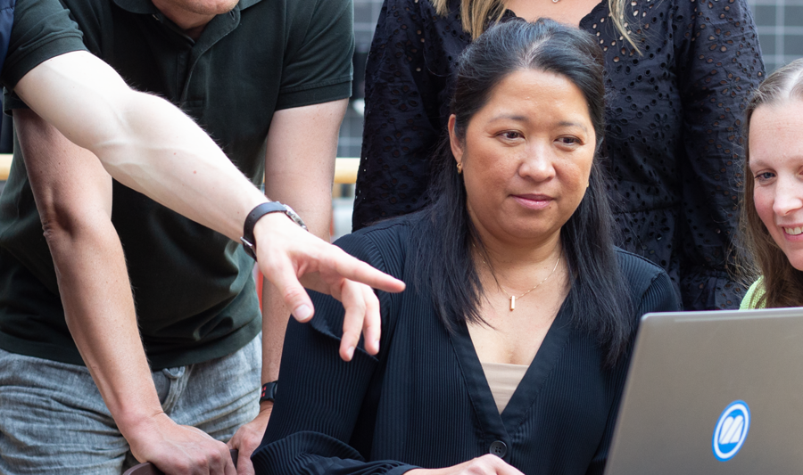 Personer sitter runt ett bord och tittar på en laptop.