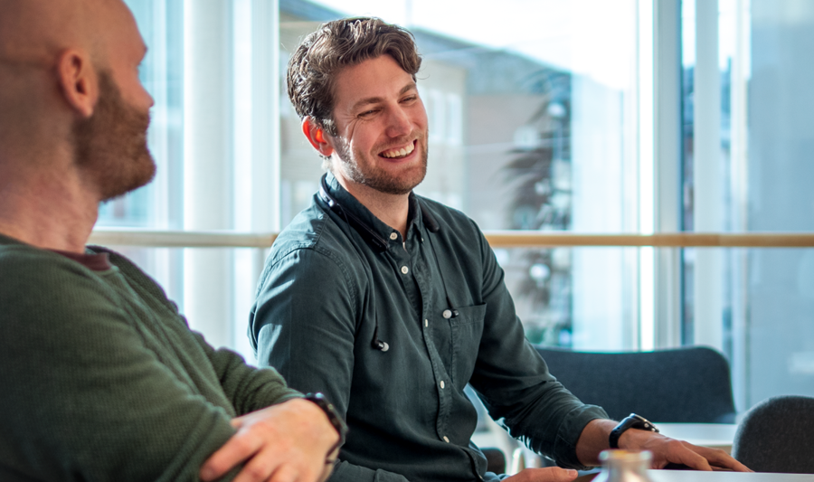 A couple of men sitting at a table with laptops.