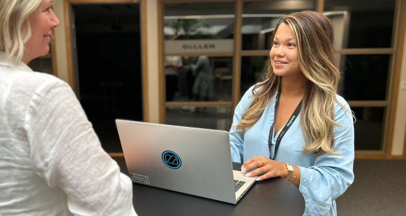 Två personer står och pratar med varandra och kollar på en laptop.