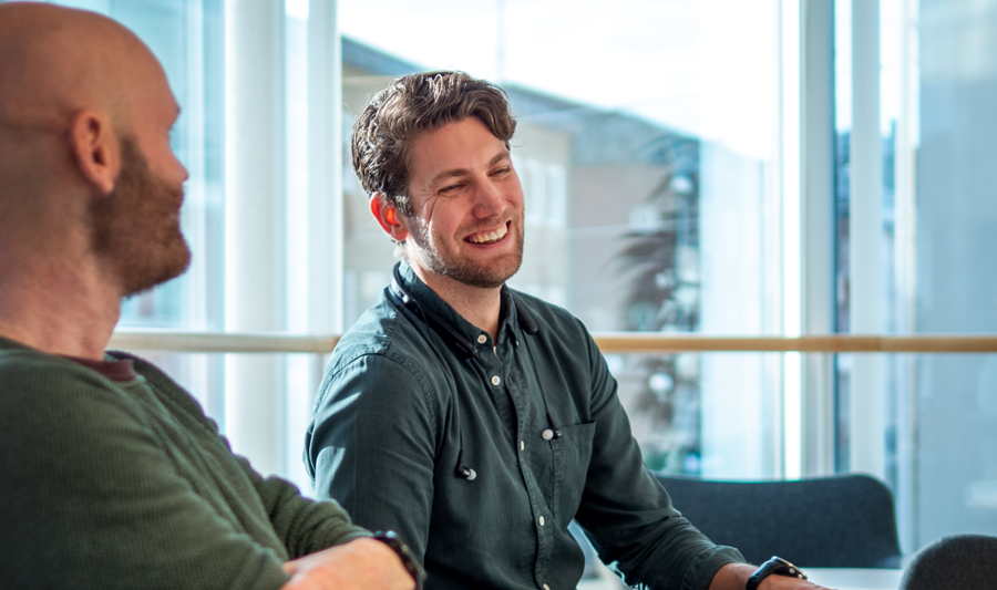A couple of men sitting at a table with laptops.