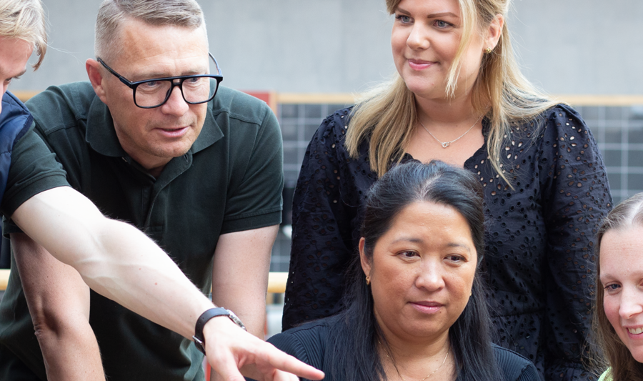 Medarbetare på Monitor står och samtalar runt ett bord.